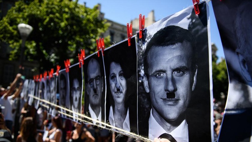 Ảnh các chính trị gia, bao gồm cả Tổng thống Macron, bị gắn bộ ria mép của Hitler, được dùng trong cuộc biểu tình ở Marseille. Ảnh: AFP (chụp ngày 17/7/2021)