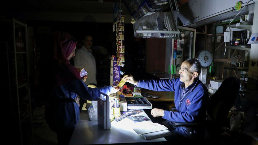 Mọi người mua sắm trong một cửa hàng tạp hóa gần Bhamdoun dưới ánh đèn sạc khi toàn quốc bị cắt điện vào ngày 9/10/2021. Ảnh: Reuters