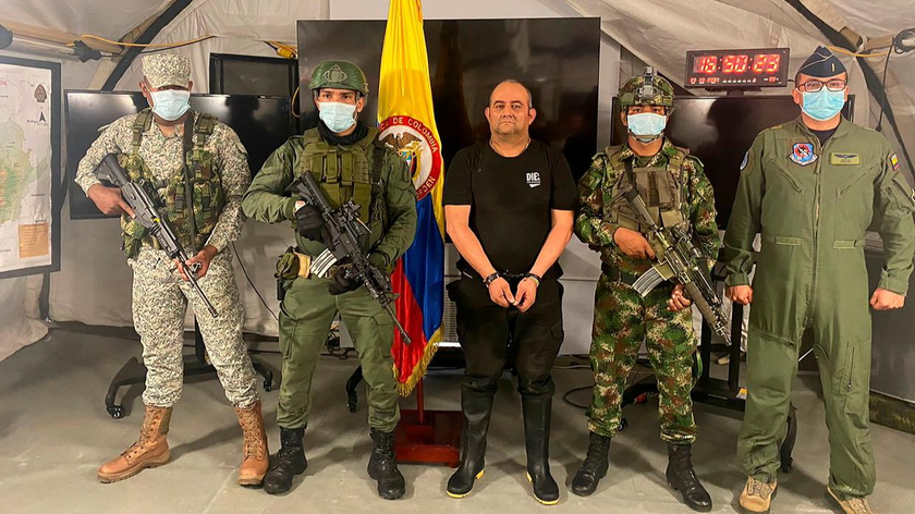 Otoniel (giữa) bị còng tay đã được giới thiệu với giới truyền thông cuối ngày 23/10, xung quanh là quân đội vũ trang đầy đủ. Ảnh: Bộ Quốc phòng Colombia/Reuters