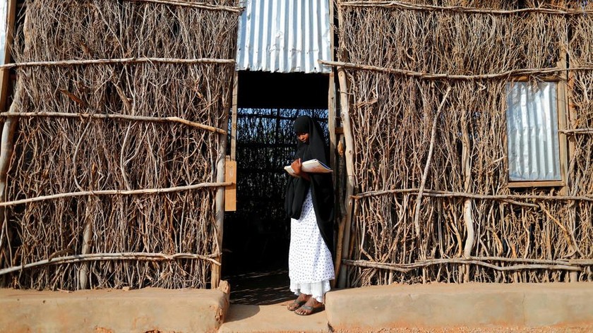 Một bé gái 14 tuổi đứng ở ngưỡng cửa một phòng học tạm ở Dollow, Somalia. Ảnh: Reuters