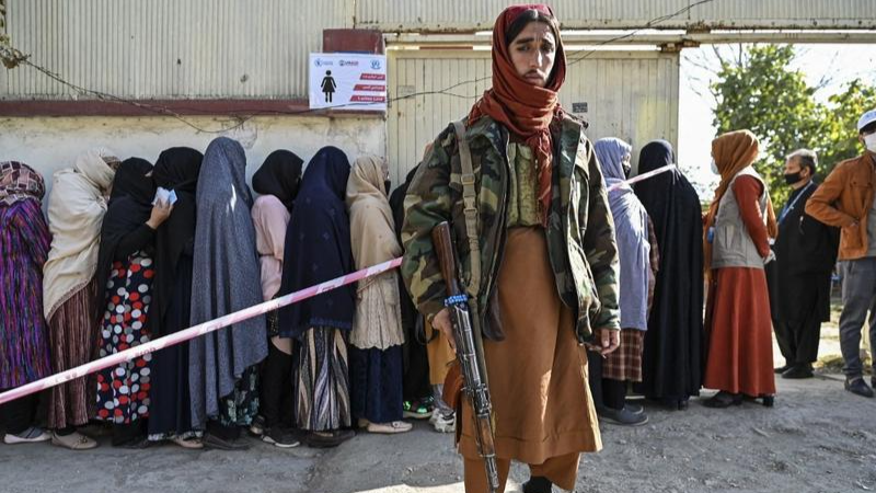 Một chiến binh Taliban đứng bảo vệ khi phụ nữ xếp hàng chờ phân phối thực phẩm của Chương trình Lương thực Thế giới ở Kabul vào ngày 6/11/2021. Ảnh: AFP