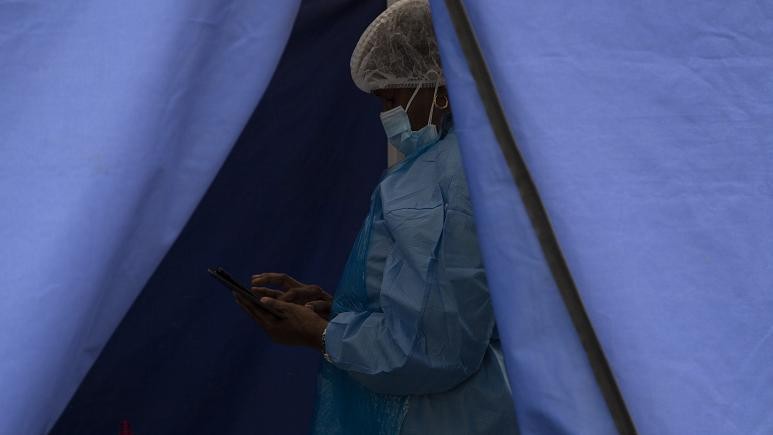 Một nhân viên y tế chờ xét nghiệm COVID-19 tại một cơ sở ở Soweto, Nam Phi. Ảnh: AP (chụp ngày 2/12/2021)