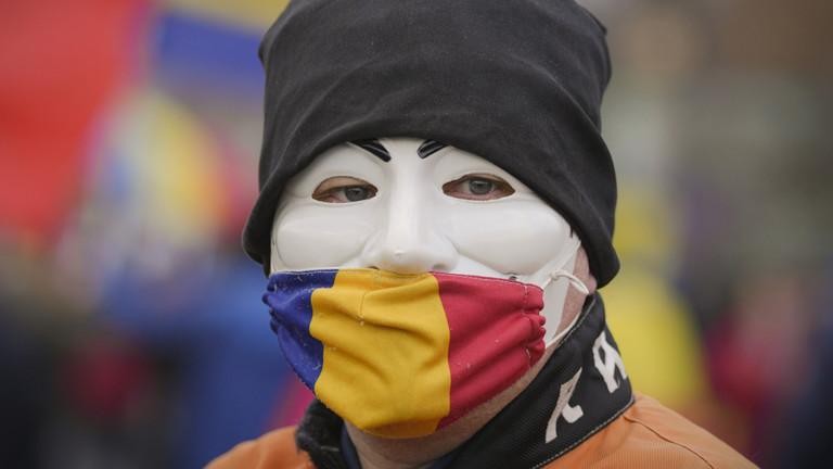 Người đàn ông đeo khẩu trang vải có màu sắc của quốc kỳ Romania trong cuộc biểu tình ở Bucharest. Ảnh: AP 