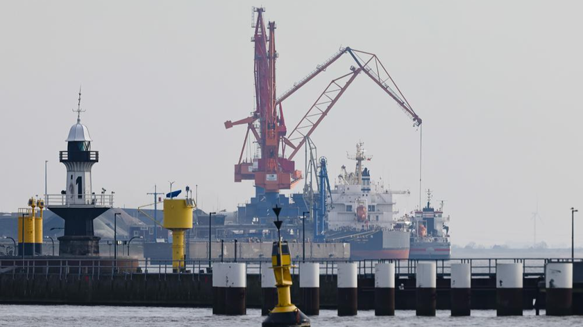 Các con tàu được bốc và dỡ hàng tại cảng Brunsbuettel, Đức. Khu vực lân cận đang được xem xét làm địa điểm cho một nhà ga LNG mới (các tuabin gió đứng trước một cơ sở lưu trữ than trên đê Elbe tại Cảng Brunsbuettel. Ảnh: dpa (chụp ngày 1/3/2022 phát qua AP)