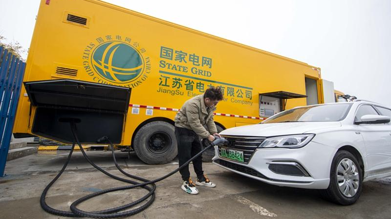 Một nhân viên sạc xe điện (EV) bằng cọc sạc di động tại khu vực dịch vụ Quảng Lăng trên đường cao tốc Bắc Kinh-Thượng Hải ở Thái Châu, tỉnh Giang Tô, miền Đông Trung Quốc, vào ngày 26/1/2022. Ảnh: cnsphoto