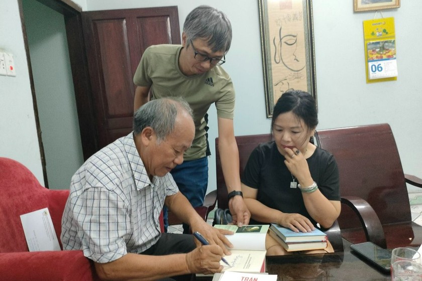 Nhà thơ Trần Nhuận Minh tặng sách và chụp ảnh lưu niệm cùng phóng viên Báo Pháp luật Việt Nam. (Ảnh: PV)