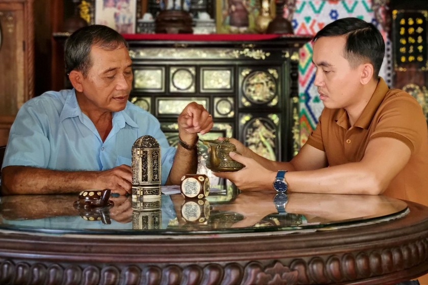 Ông Nguyễn Văn Chẳng (trái) giới thiệu những món đồ cổ nằm trong bộ sưu tập.