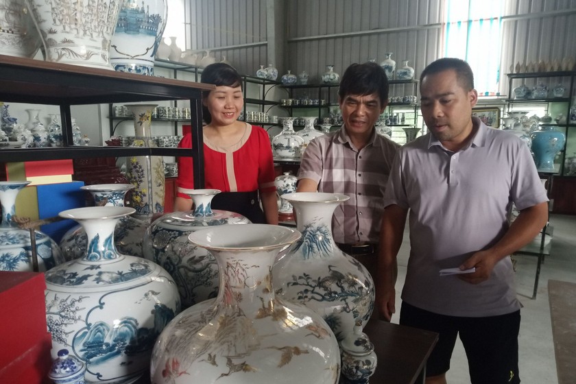 Nghệ nhân Phạm Văn Vang (bên phải ngoài cùng) đang giới thiệu sản phẩm cho khách hàng.