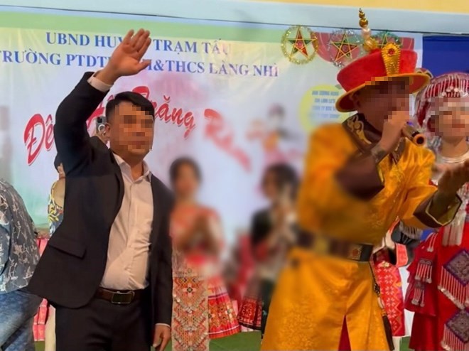 Phú Lê mặc trang phục giống vua xuất hiện trong lễ trao quà tại một trường học. (Ảnh chụp màn hình). 