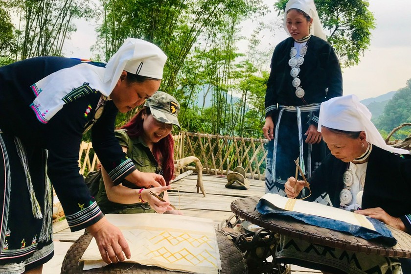 Những người phụ nữ dân tộc Dao Tiền hướng dẫn cách vẽ và in sáp ong cho du khách. (Ảnh: Bảo Châu)
