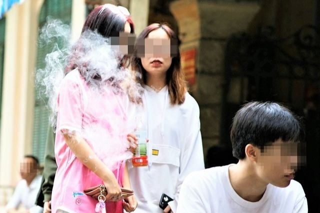 Học sinh sử dụng thuốc lá điện tử trước cổng trường học. (Nguồn ảnh: SKĐS)