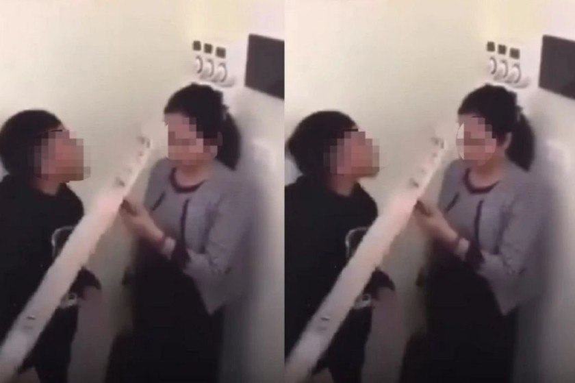 Hình ảnh cắt từ video cô giáo bị học sinh dồn vào góc tường, cầm gậy chỉ vào mặt thách thức.