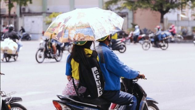 Cầm ô khi đang đi xe máy bị xử phạt thế nào?