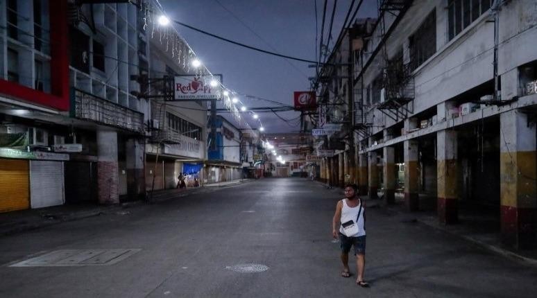 Một người đàn ông đi ngang qua các cửa hàng đóng cửa trong một con đường vắng sau khi có lệnh phong tỏa ở thủ đô Philippines. Ảnh: REUTERS 