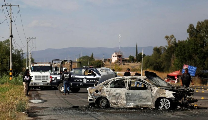 Cảnh sát đứng bên đống đổ nát của một chiếc ô tô bị đốt cháy ở ngoại ô Celaya, Guanajuato, Mexico. Ảnh: Reuters