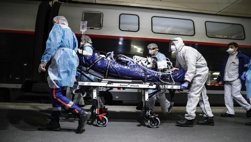 Nhân viên y tế chuyển một bệnh nhân bị nhiễm Covid-19 sang một chuyến tàu tại nhà ga Voyusterlitz ở Paris. Ảnh: AP