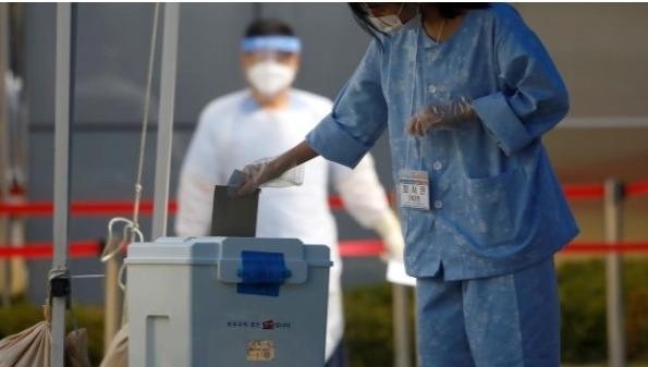 Một bệnh nhân Hàn Quốc bị nhiễm COVID-19 bỏ phiếu bầu cử quốc hội tại một điểm bỏ phiếu được thiết lập trong một trung tâm kiểm dịch ở Yongin , Hàn Quốc, ngày 11/4/2020. Ảnh: Reuters.