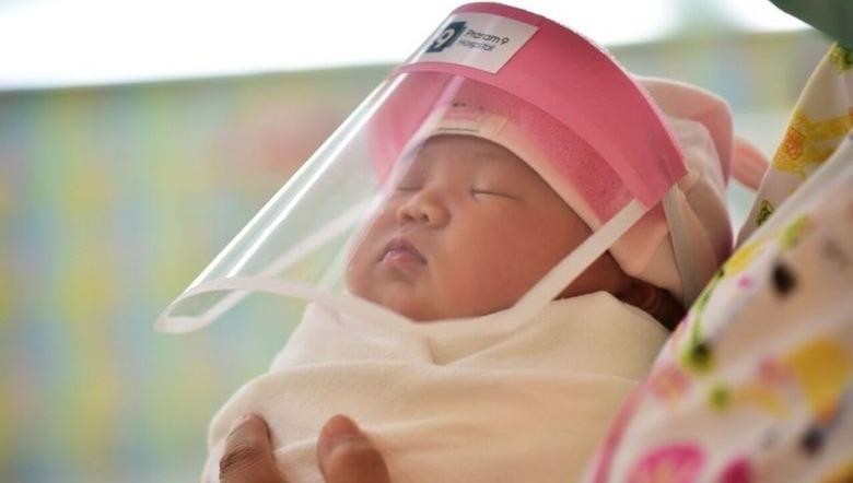 Một em bé sơ sinh đeo tấm che mặt ở Bangkok. Ảnh: AFP