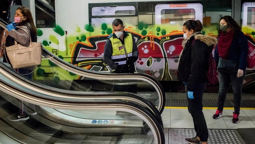 Một nhân viên bảo vệ kiểm soát khoảng cách giữa những người đi lại trên thang cuốn tại ga Catalunya ở Barcelona. 