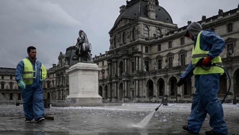 Công nhân đang rửa đường phía trước bảo tàng Louvre ở Paris (Pháp). Ảnh: AFP