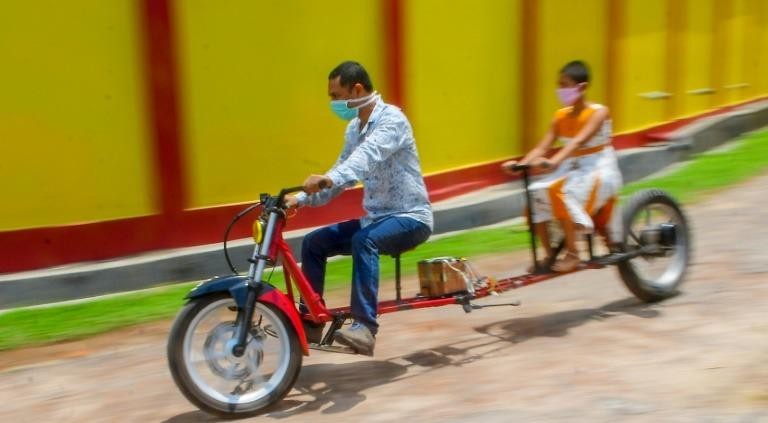 Anh Partha Saha (trái) đã chế tạo một chiếc xe máy đảm bảo giãn cách xã hội.