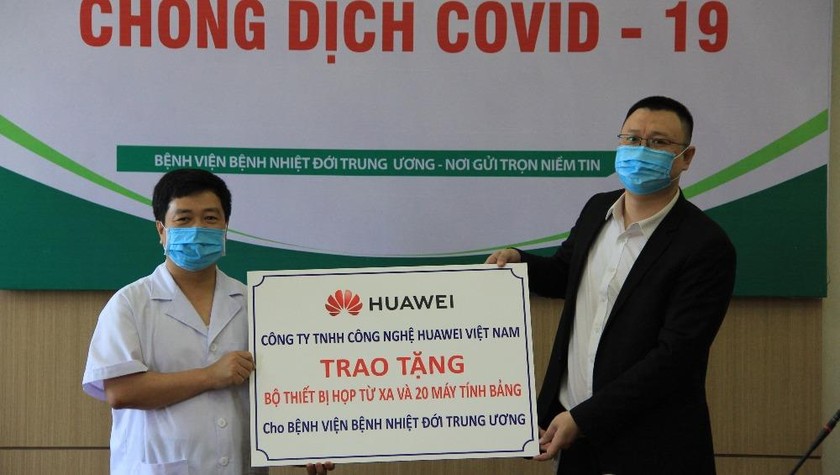 Đại diện Cty TNHH Công nghệ Huawei Việt Nam (phải) trao tặng Bộ thiết bị giải pháp hội nghị truyền hình và 20 máy tính bảng cho đại diện Bệnh viện Bệnh Nhiệt đới Trung ương.