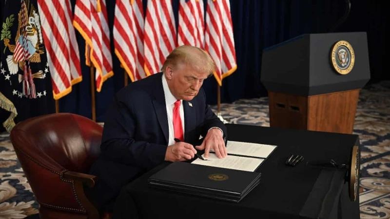 Tổng thống Mỹ Donald Trump ký sắc lệnh gia hạn cứu trợ kinh tế trong cuộc họp báo ở New Jersey hôm 8/8. Ảnh: AFP.