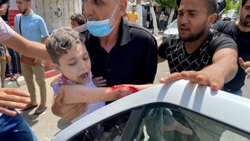 Một cậu bé Palestin bị thương do không kích của Israel đang được bố đưa đến bệnh viện.