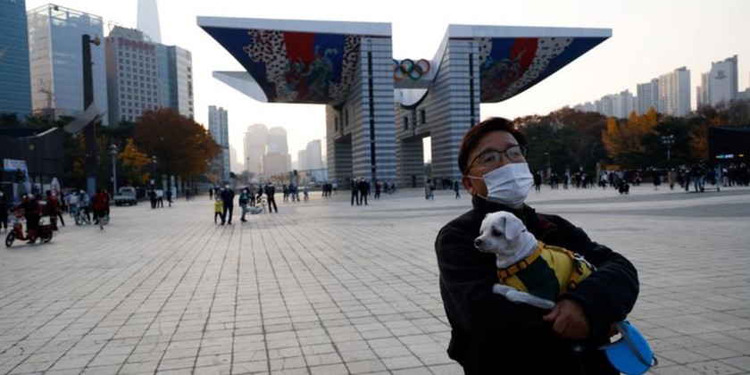 Một người đàn ông ôm chó cưng đi dạo tại một công viên ở Seoul, Hàn Quốc. Ảnh: REUTERS.