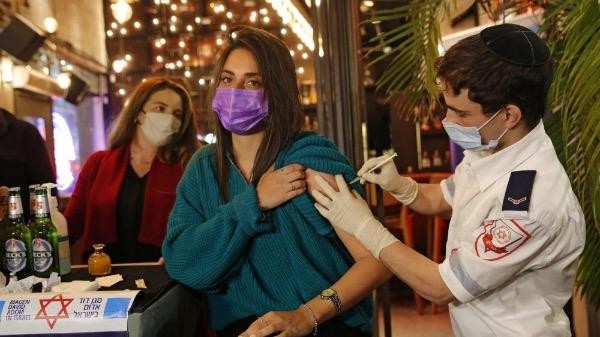 Nhân viên y tế tiêm vaccine ngừa Covid-19 cho một người Israel tại một quán bar ở Tel Aviv. 