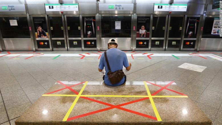 Người dân ngồi trước ga tàu điện ngầm ở Singapore thời dịch bệnh. Ảnh: Getty.