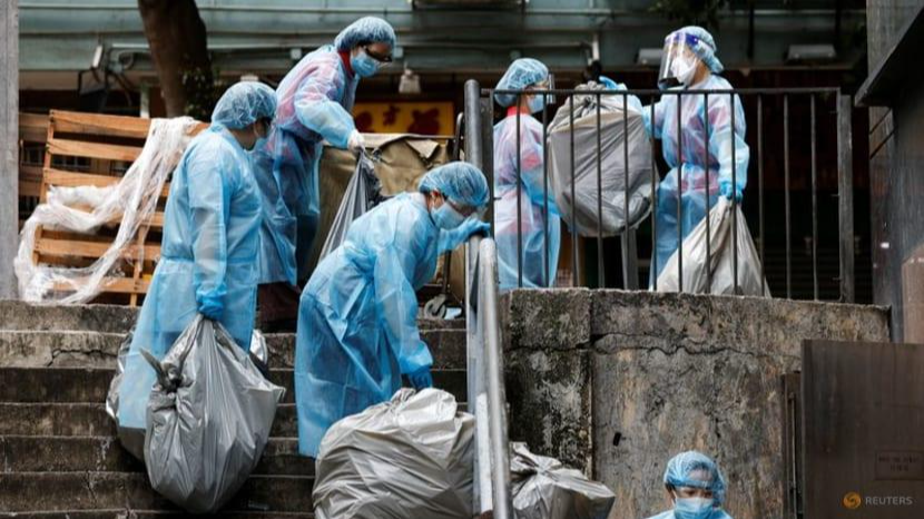 Các nhân viên vệ sinh mặc đồ bảo hộ bỏ rác tại 1 khách sạn cách ly ở Hong Kong. Ảnh: Reuters.
