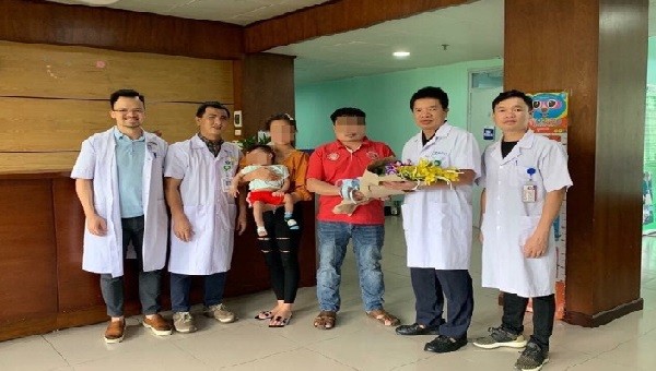 Các bác sĩ tặng hoa chúc mừng gia đình bệnh nhi.