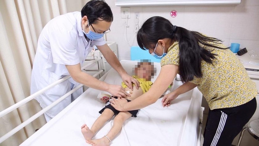 BS Nguyễn Đức Lân kiểm tra lại vết mổ cho trẻ trước khi xuất viện.