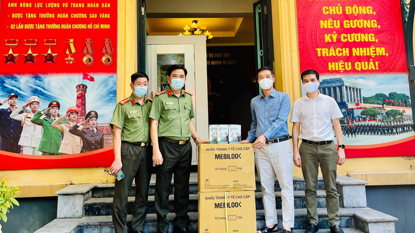 Đại tá Trần Đình Nghĩa Trưởng phòng tham mưu, CATP Hà Nội (đứng thứ 2 từ trái qua) nhận 5.000 khẩu trang do Tập đoàn dược phẩm AIKYA trao tặng.