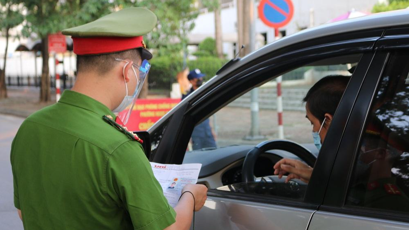 Cán bộ cảnh sát kiểm tra giấy tờ của người đi đường tại Hà Nội. Ảnh: Ngọc Nga
