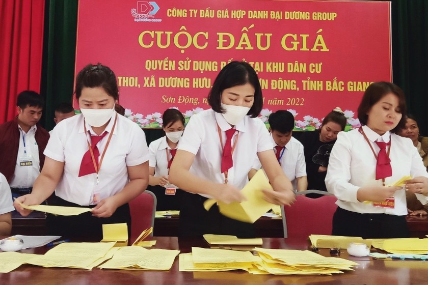 Bà Nguyễn Ngọc Luyên( mặc áo trắng đứng đầu tiên bên phải) đang mở phiếu đấu giá tại 1 buổi đấu giá quyền sử dụng đất tại khi dân cư trên địa bàn tỉnh Bắc Giang. (Nguồn ảnh daibieunhandan.vn)