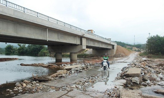 Người dân lội nước vượt suối bên cây cầu đã hoàn thành nhưng thiếu đường dẫn