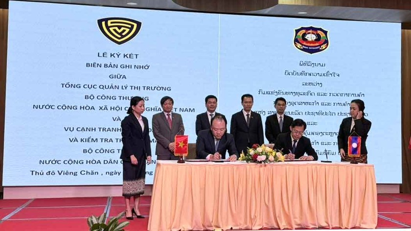 Tổng Cục trưởng Trần Hữu Linh và Vụ trưởng Vụ Cạnh tranh kinh doanh và Kiểm tra Thương mại Lào triển khai ký cam kết dưới sự chứng kiến của Bộ trưởng hai Bộ.