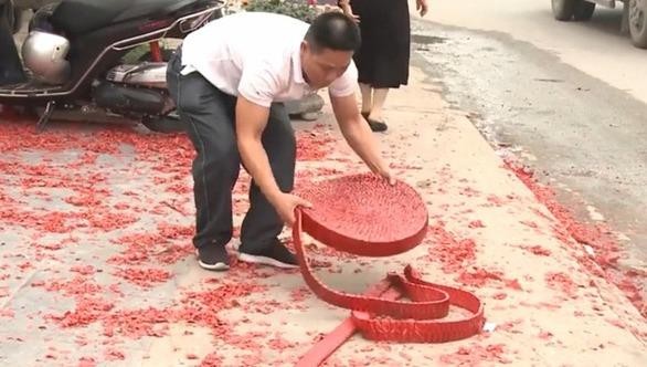 Người đàn ông rải cuộn pháo ra vỉa hè, trước ngôi nhà tổ chức đám cưới. Ảnh: Facebook.