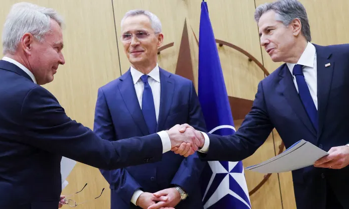 Ngoại trưởng Phần Lan Pekka Haavisto (bên trái) bắt tay Ngoại trưởng Mỹ Antony Blinken với sự chứng kiến của Tổng thư ký NATO Stoltenberg (ở giữa) khi ông Blinken trao văn bản về việc Phần Lan gia nhập NATO. 