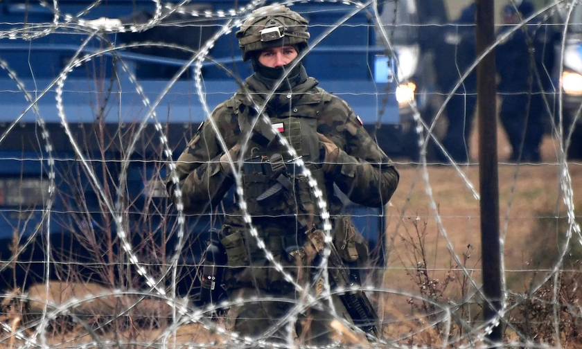 Một binh sỹ Ba Lan đứng gác sau hàng rào thép gai ở biên giới với Belarus. 