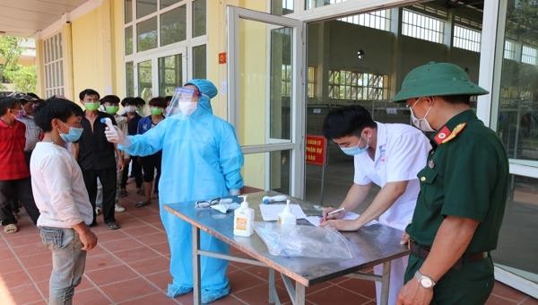  Cán bộ y tế đo thân nhiệt cho công dân Việt Nam từ Trung Quốc trở về. Ảnh: Thu Huyền