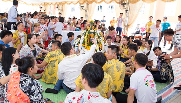 Mọi người ngồi xung quanh đài hoa lớn tiến hành nghi lễ té nước và buộc chỉ cổ tay.
