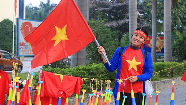 Một tiểu thương bán đồ cổ vũ cho đội tuyển Việt Nam rạng rỡ trong sắc cờ đỏ sao vàng.