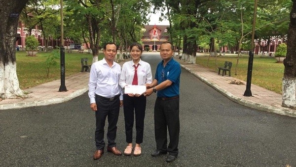 Nhà báo Nguyễn Quang Tám - Trưởng Văn phòng Đại diện Báo PLVN khu vực Bình Trị Thiên (trái) trao số tiền bạn đọc  ủng hộ em Nhung.