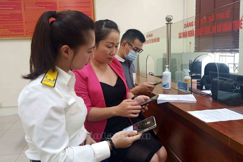 Cán bộ thuế hướng dẫn người dân cài đặt và sử dụng ứng dụng eTax Mobile trên điện thoại di động. (Nguồn ảnh: baolaichau.vn).