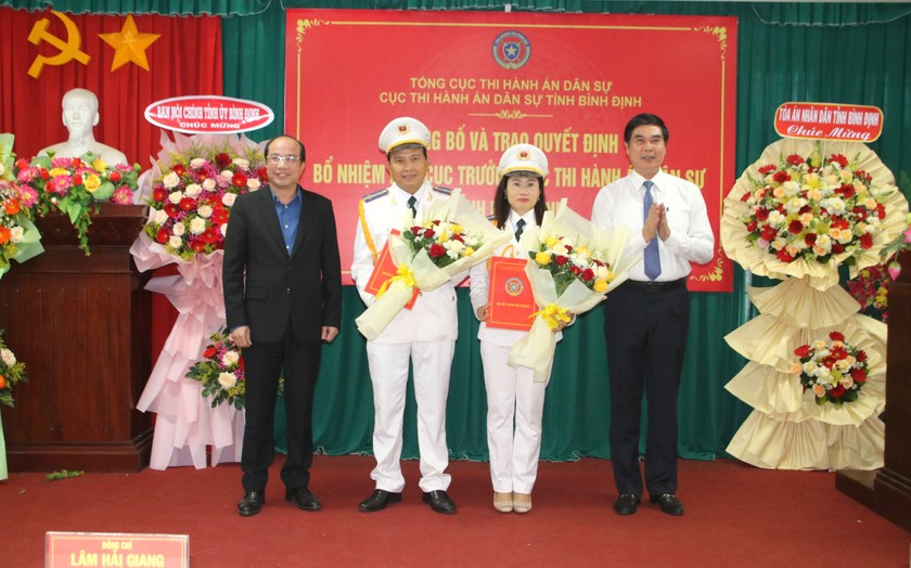 Ông Nguyễn Thắng Lợi (trái), ông Lâm Hải Giang (phải) trao các quyết định bổ nhiệm và tặng hoa cho 2 tân Phó Cục trưởng Cục THADS tỉnh Bình Định.