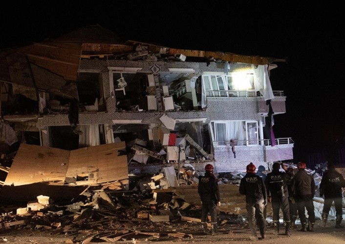 Các nhân viên cứu hộ đứng trước một tòa nhà bị đổ do trận động đất tối 20/2. Ảnh: Anadolu. 