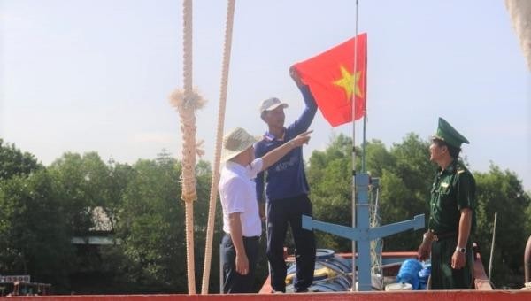 Phó Tổng biên tập Trần Đức Vinh (bìa trái) cùng ngư dân treo cờ trên nóc tàu cá
